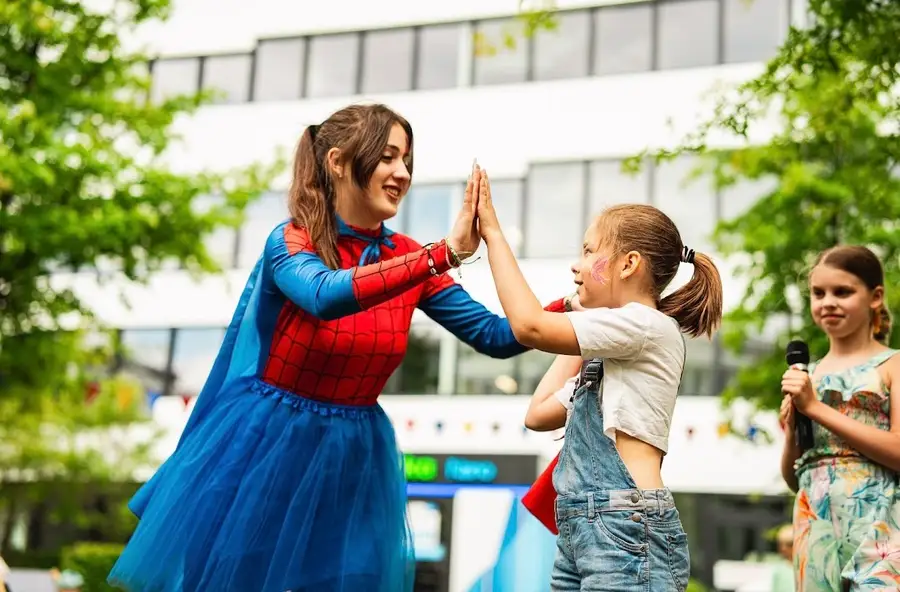 Animatorka w stroju superbohaterki przybija piątkę dziewczynce na pikniku firmowym